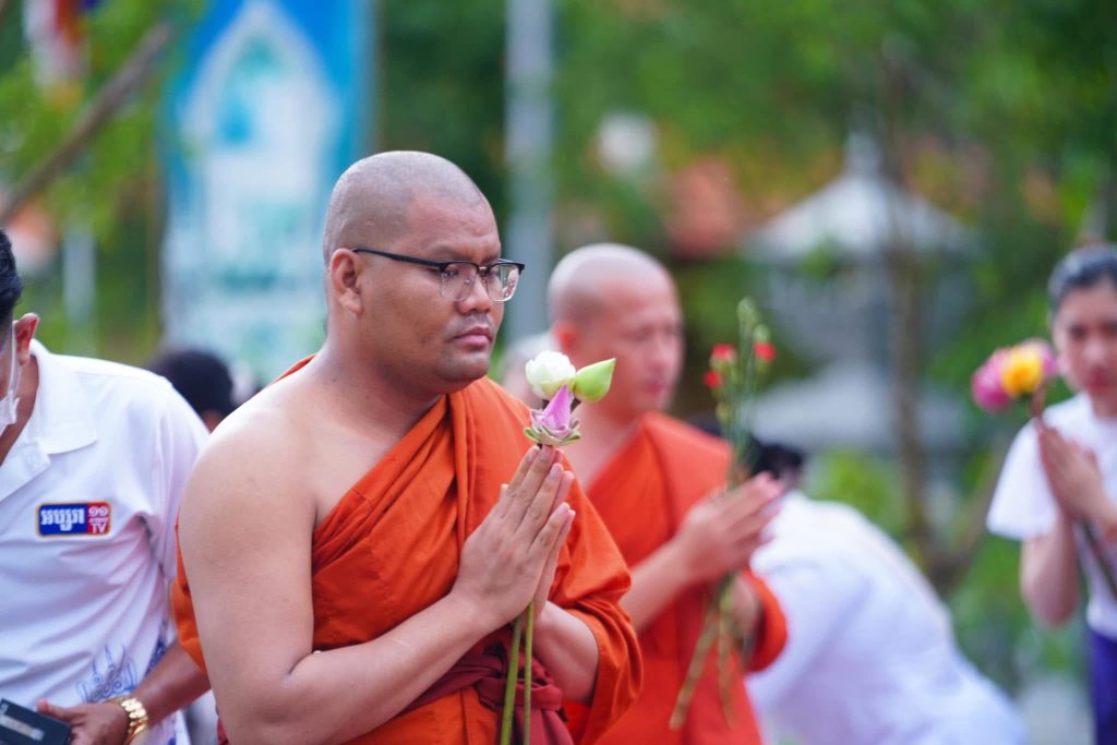 Buddhist monk holding a lotus flower during a ceremony