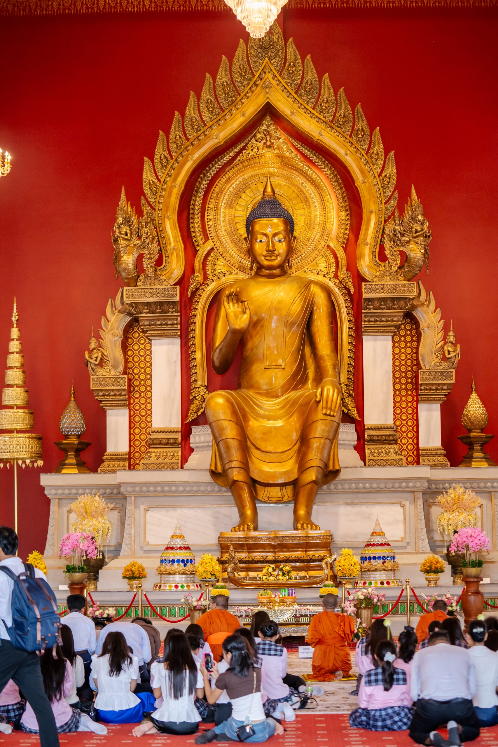 Golden Buddha statue in a Cambodian temple with visitors paying respect